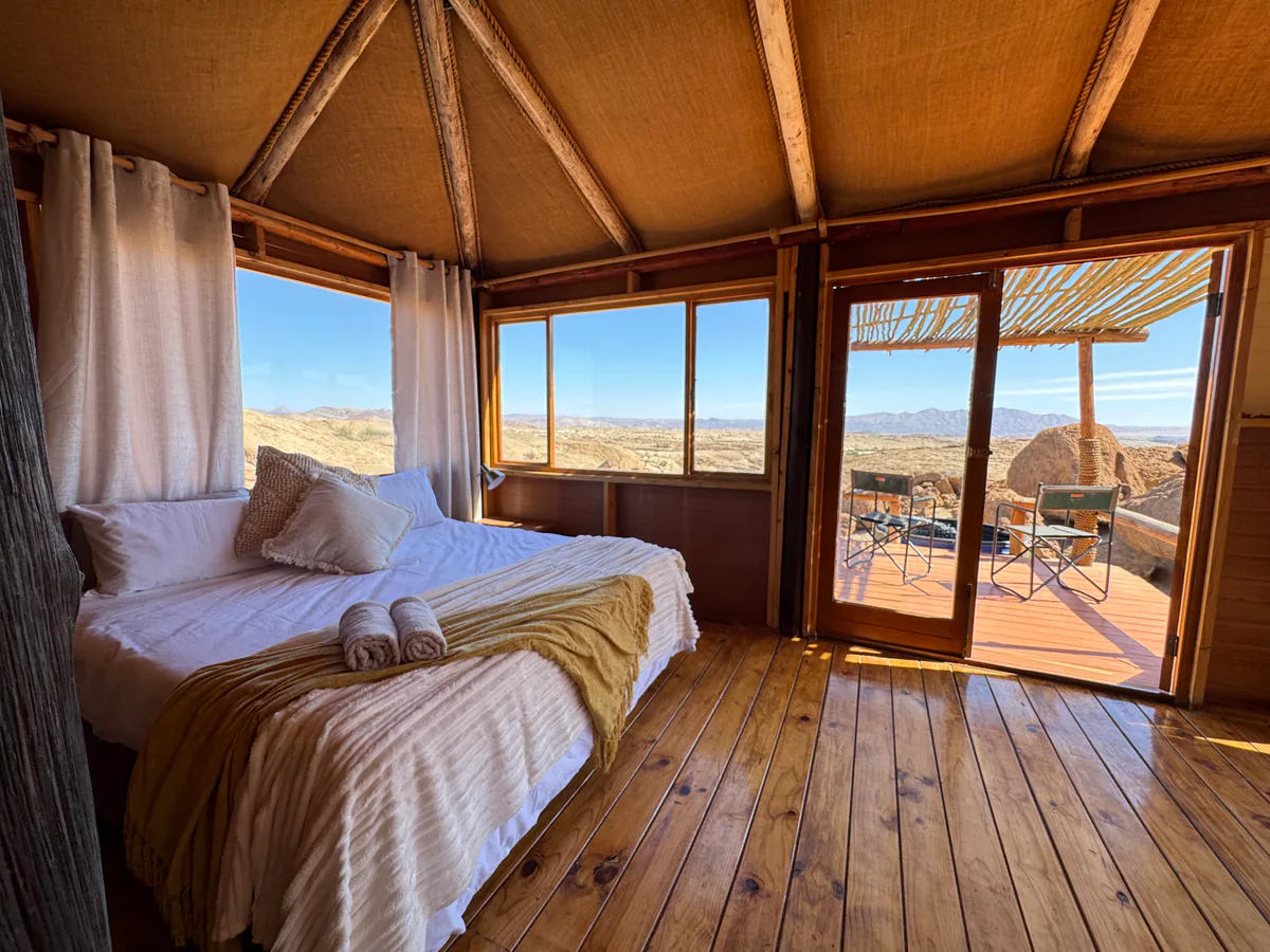 A bedroom in the Mountain Chalet overlooking the desert landscape at Wüstenquell Conservation Farm.