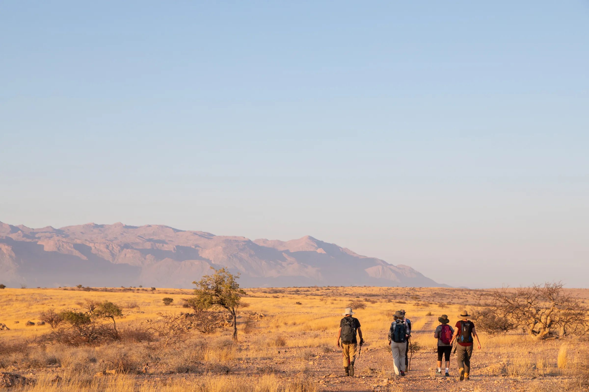Hikers crossing open conservancy country towards distant mountains.