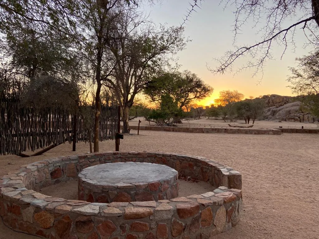 An overland campsite fire ring at sunset at Madisa.
