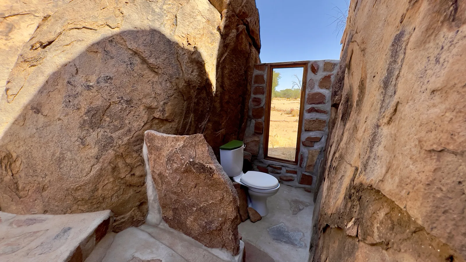 An open-air Safari Tent bathroom built into granite boulders.