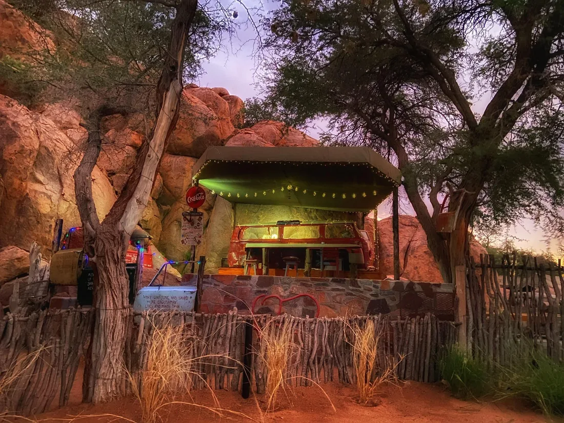 The raised-deck bar at Madisa Camp glowing beneath the granite at dusk.